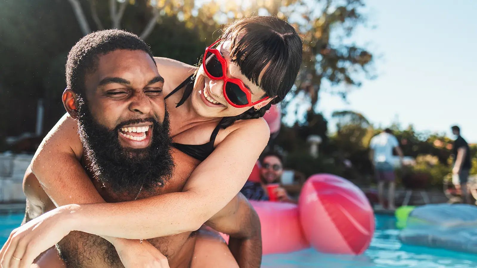 1600x900_MixedCoupleHoldingEachotherPlayfullyAtbackyardPoolParty